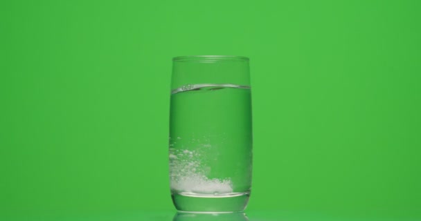 Pacient hodí aspirin do sklenice vody na zeleném pozadí — Stock video