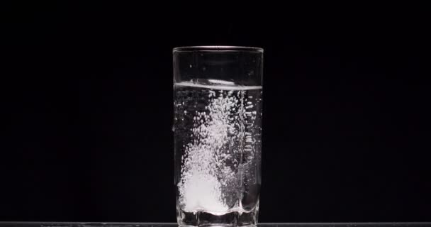 Patient wirft Aspirin in ein Glas Wasser auf schwarzem Hintergrund — Stockvideo