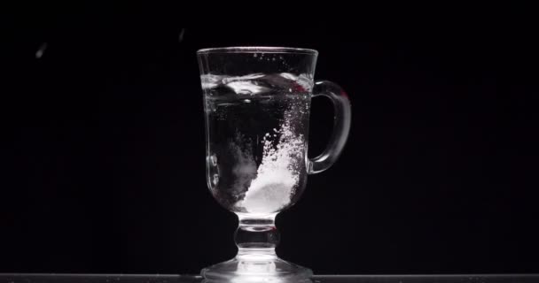 Paciente arroja aspirina en un vaso de agua sobre un fondo negro — Vídeo de stock