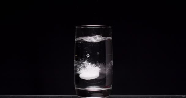 Patiënt gooit aspirine in een glas water op een zwarte achtergrond — Stockvideo