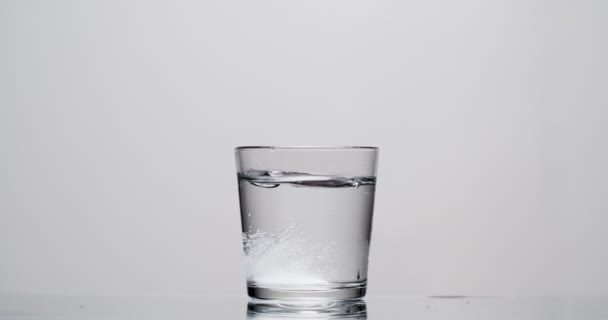 patient jette de l'aspirine dans un verre d'eau sur fond blanc 