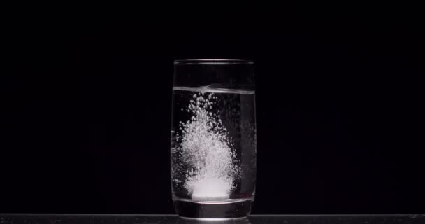 patient jette de l'aspirine dans un verre d'eau sur un fond noir 