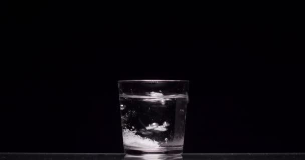 patient jette de l'aspirine dans un verre d'eau sur un fond noir 
