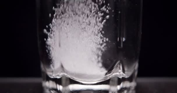 patient jette de l'aspirine dans un verre d'eau sur un fond noir 