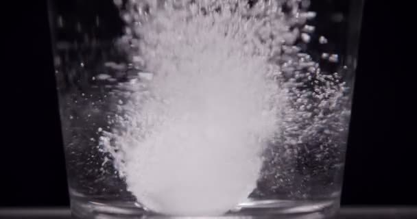 Patient throws aspirin into a glass of water on a black background — Stock Video