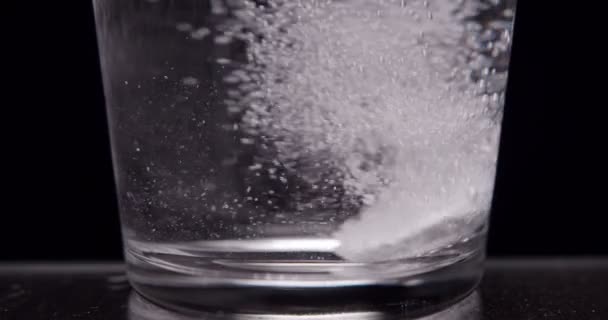 Paciente arroja aspirina en un vaso de agua sobre un fondo negro — Vídeo de stock