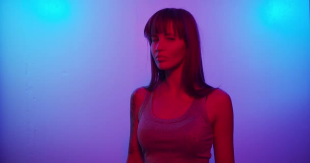Fashion model girl Turns to the camera and looks in neon light — Stock video