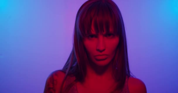 Fashion model girl Turns to the camera and looks in neon light — ストック動画