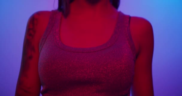 Дівчина моделі моди повертається до камери і дивиться в неонове світло — стокове відео