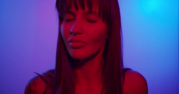 Turns to the camera and looks and smiles, cute looks in neon light — Stok video