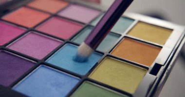 Make-up artist dips a brush in blue palette