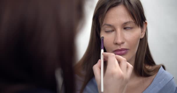 Artista de maquillaje profesional aplicando maquillaje en la cara modelos antes de desfile de moda — Vídeo de stock