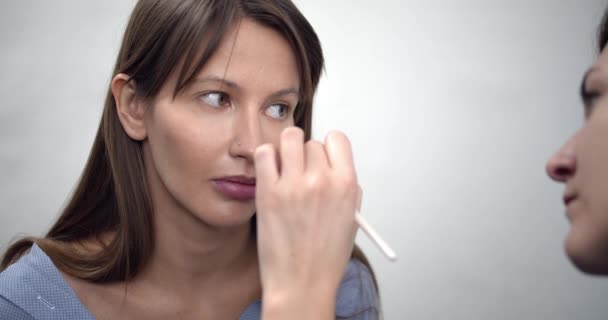 Artista de maquillaje profesional aplicando maquillaje en la cara modelos antes de desfile de moda — Vídeos de Stock