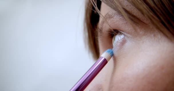 L'artista di trucco professionale fa il trucco di modello giovane. Vista da vicino della mano del make-up artist applicando ombretto con pennello speciale alla giovane donna per partecipare alla sfilata. Bellezza e Moda — Video Stock