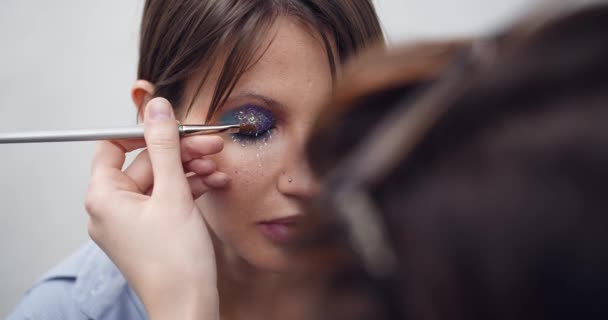 Glitter tillämpas på kvinnans ögonlocket, att göra kvällsmakeup, ögon makeup, makeup artister arbete, närbild makeup — Stockvideo