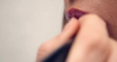 makeup artist works with the model, applies lipstick with a brush on the lips of the model, close-up macro. paints lips.