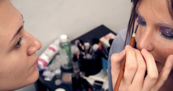 Portrait of brunette girl, makeup artist eyelashes of model eyes in makeup studio. Makeup and beauty — Stock video