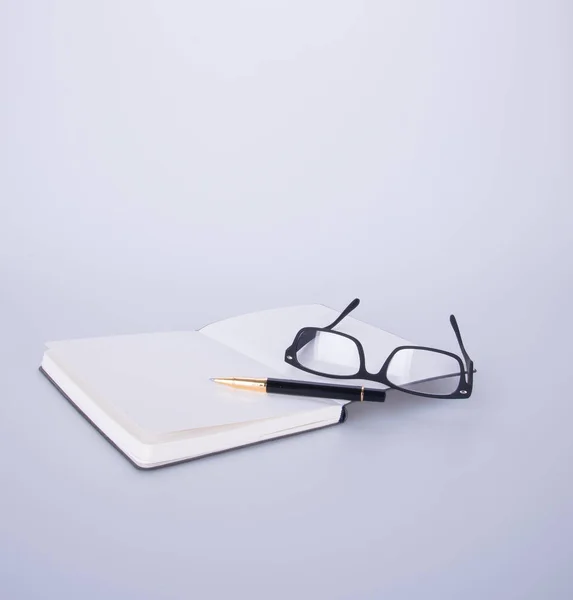 Notizbuch mit Brille und Stift auf dem Schwarzgrund. — Stockfoto