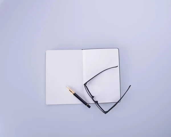 Notizbuch mit Brille und Stift auf dem Schwarzgrund. — Stockfoto