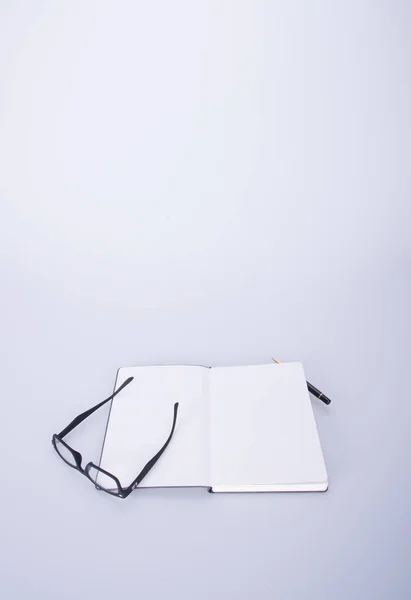 Notizbuch mit Brille und Stift auf dem Schwarzgrund. — Stockfoto