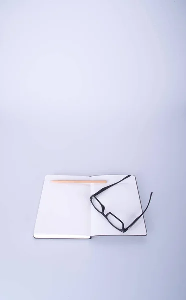 Notizbuch mit Brille und Stift auf dem Schwarzgrund. — Stockfoto