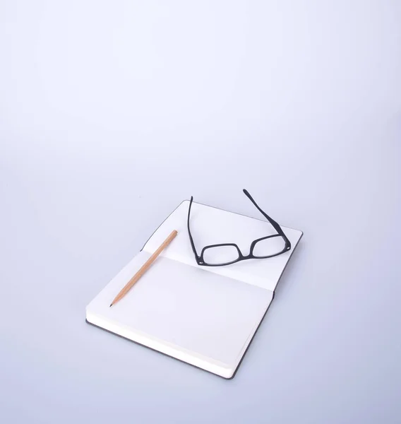 Notizbuch mit Brille und Stift auf dem Schwarzgrund. — Stockfoto