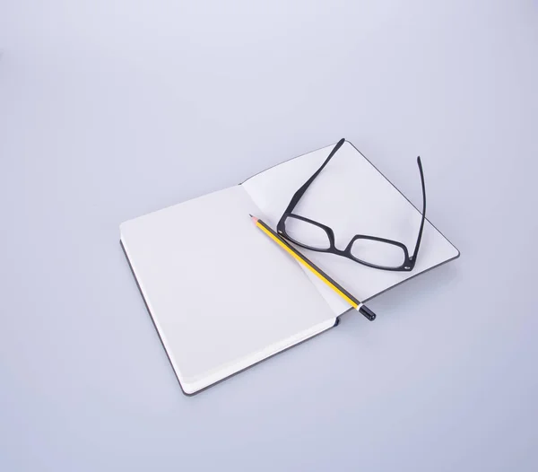 Ноутбук с очками и ручкой на черном поле . — стоковое фото