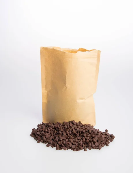 Chocolate chip morsels spread and paper bag. — Stock Photo, Image