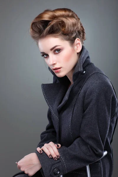 Portrait de jeune femme élégante en manteau gris sur fond gris — Photo