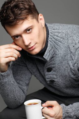 Onun elinde çay ile sıcak örgü sweateron seksi genç adam. Erkek model. 