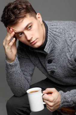 Onun elinde çay ile sıcak örgü sweateron seksi genç adam. Erkek model. 