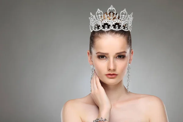 戴皇冠的漂亮女孩在灰色演播室背景上摆出一顶王冠 — 图库照片
