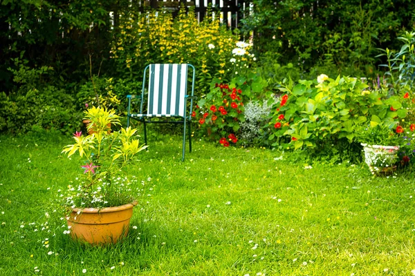 Casa giardino con una sedia e fiori vari Immagine Stock