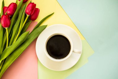 Kırmızı bahar laleleri arka planda bir fincan kahveyle