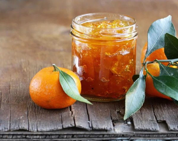 Sylt av citrusfrukt mandarin i en glasburk på ett träbord — Stockfoto