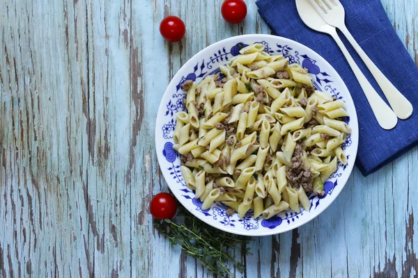 Massa penne com carne e ervas em uma mesa de madeira — Fotografia de Stock