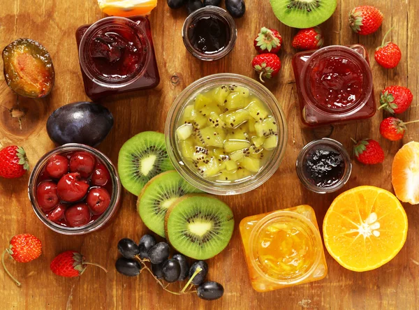 Surtido de bayas y mermeladas de frutas. Enlatado casero. Bayas y frutas frescas — Foto de Stock