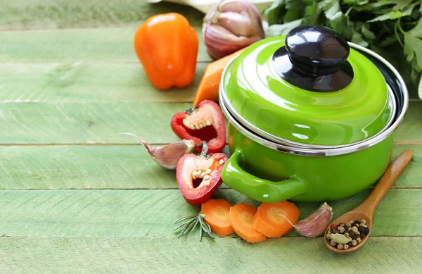 Зелений горщик для приготування їжі та інгредієнти для супу або тушкованого на сільському фоні — стокове фото