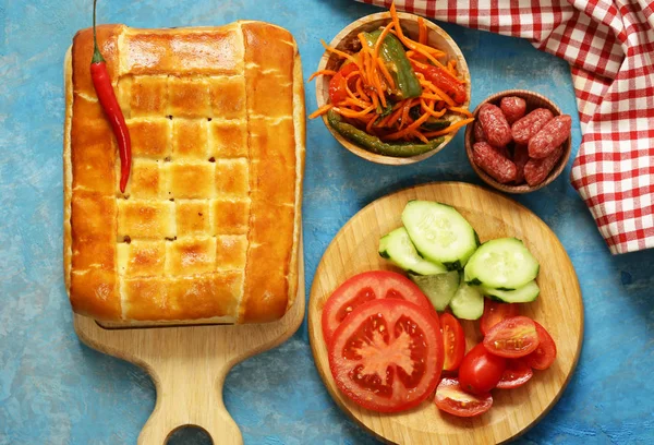 Lunch picnic table homemade meat pie with salad and salami, top view — Stock Photo, Image