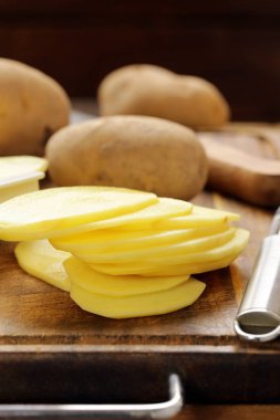 Bir kesme tahtası üzerinde soyulmuş ve dilimlenmiş ham patates