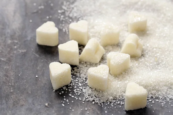 Granulated sugar and refined in the shape of heart on a wooden background — Stock Photo, Image