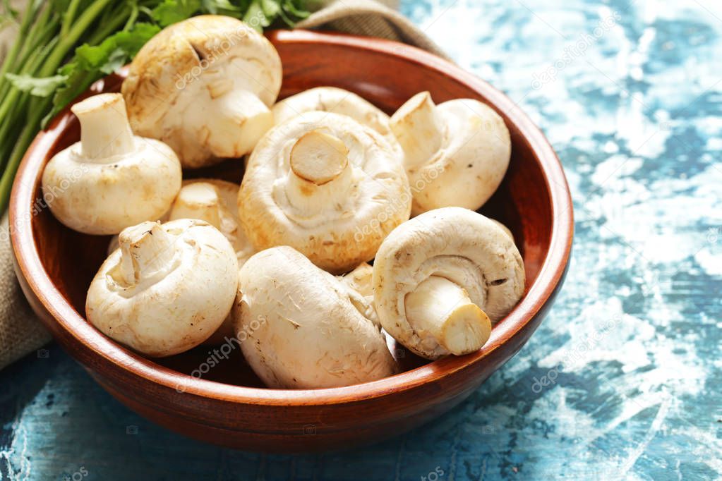 organic mushrooms champignons in a wooden bowl on the table