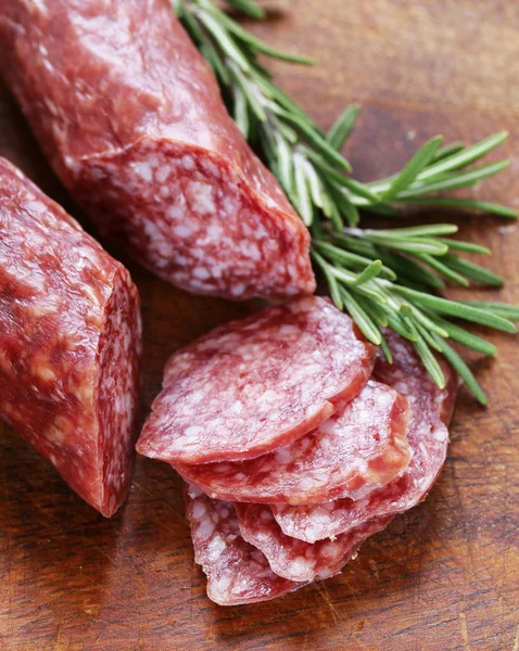 Salchicha de salami con romero en una tabla de madera — Foto de Stock