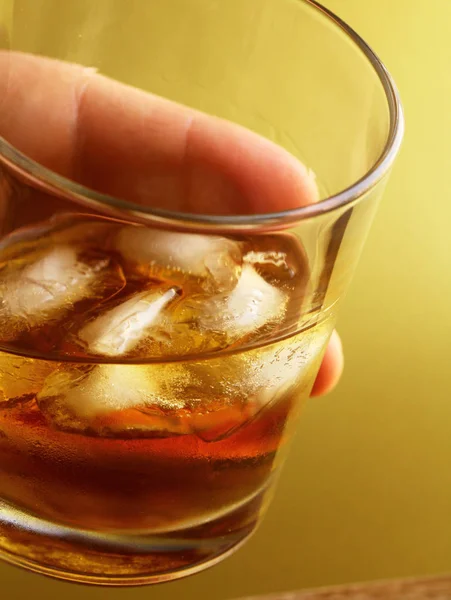 Glas Whisky mit Eis auf goldenem Hintergrund — Stockfoto