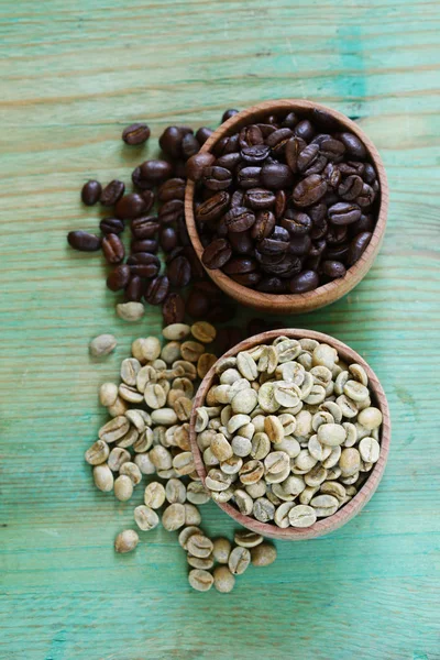 Grãos de café verde e marrom em um fundo de madeira — Fotografia de Stock