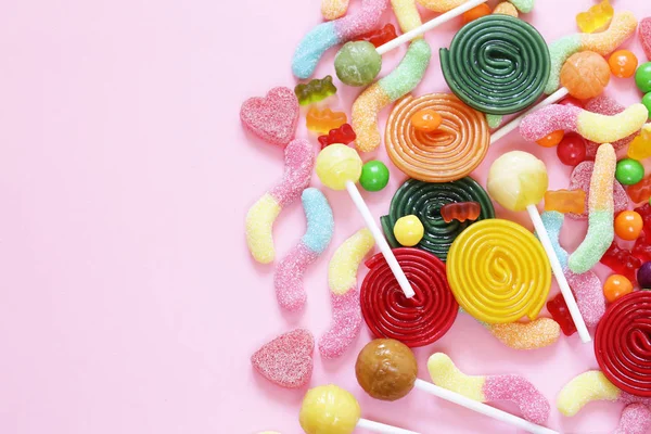 Caramelle colorate e giuggiola di gelatina di frutta su uno sfondo rosa — Foto Stock