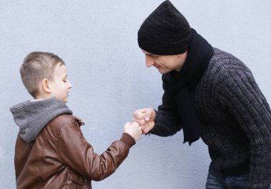 Adam ve çocuk (baba ve oğul) gri bir arka plan üzerinde poz