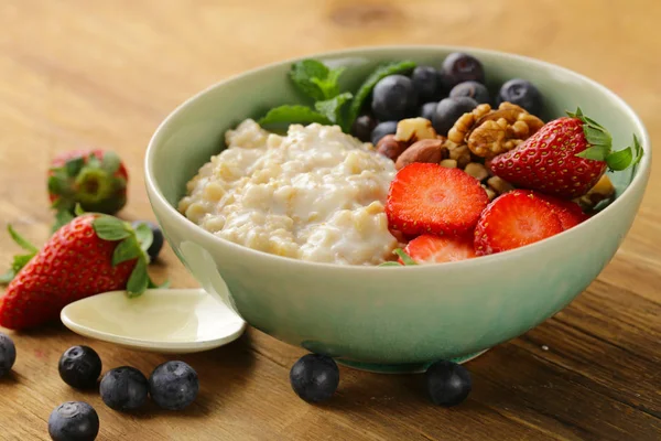 Gachas de avena con frutos secos y bayas para un desayuno saludable —  Fotos de Stock