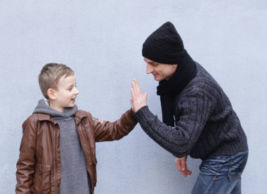 Adam ve çocuk (baba ve oğul) gri bir arka plan üzerinde poz