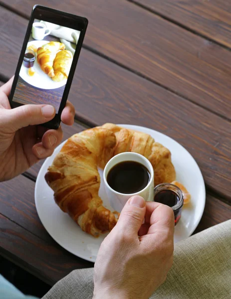 Frukost croissant med kaffe - foto på telefon — Stockfoto